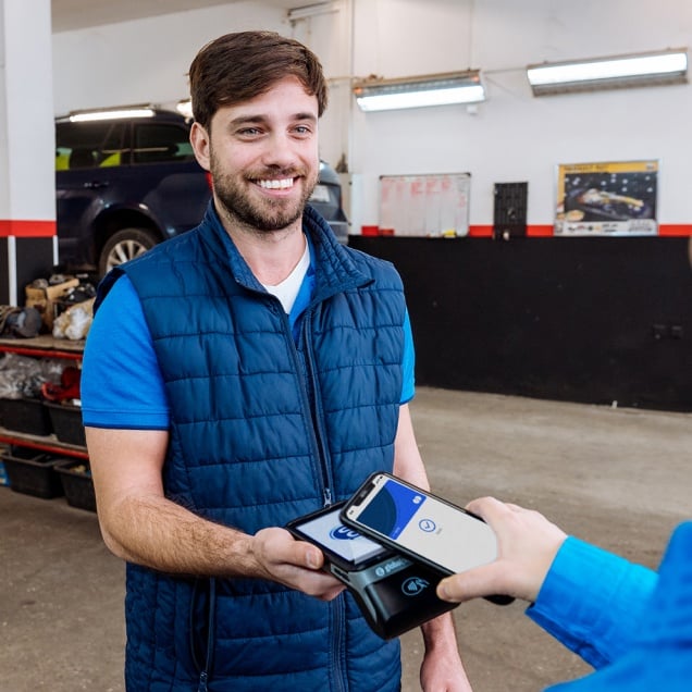 Customer waves a phone over a Global Payments POS, while a car salesman takes a secure payment