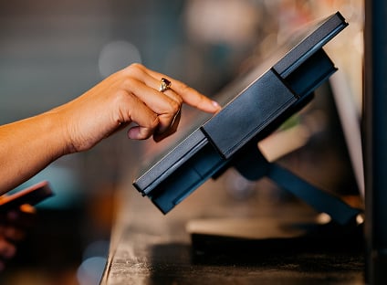a customer hand typing on a credit card terminal