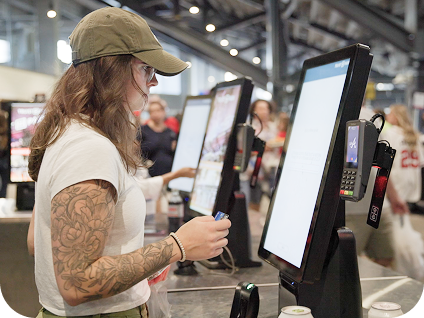 Event guest stands in front of self-order kiosk in the concourse of a venue