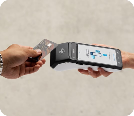 Hand tapping a credit card on a black mobile POS terminal