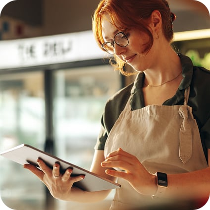 Woman wearing an apron looking down at mobile tablet POS
