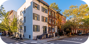 A picture of a row of properties, including a white building and apartments with brick exterior. 