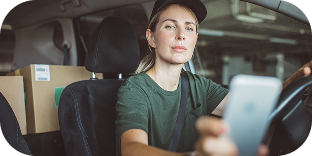 A woman making deliveries sits in a parked delivery truck inside a parking garage. 