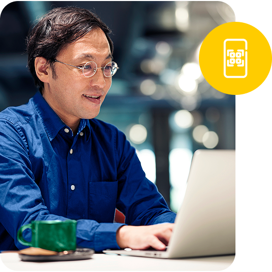 A sitting man looks at his open laptop as he types and a small graphic circle overlays the image.