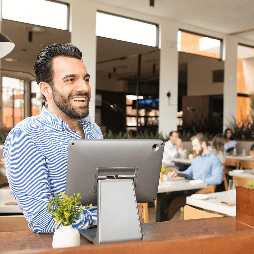 Man smiling and standing behind restaurant checkout counter