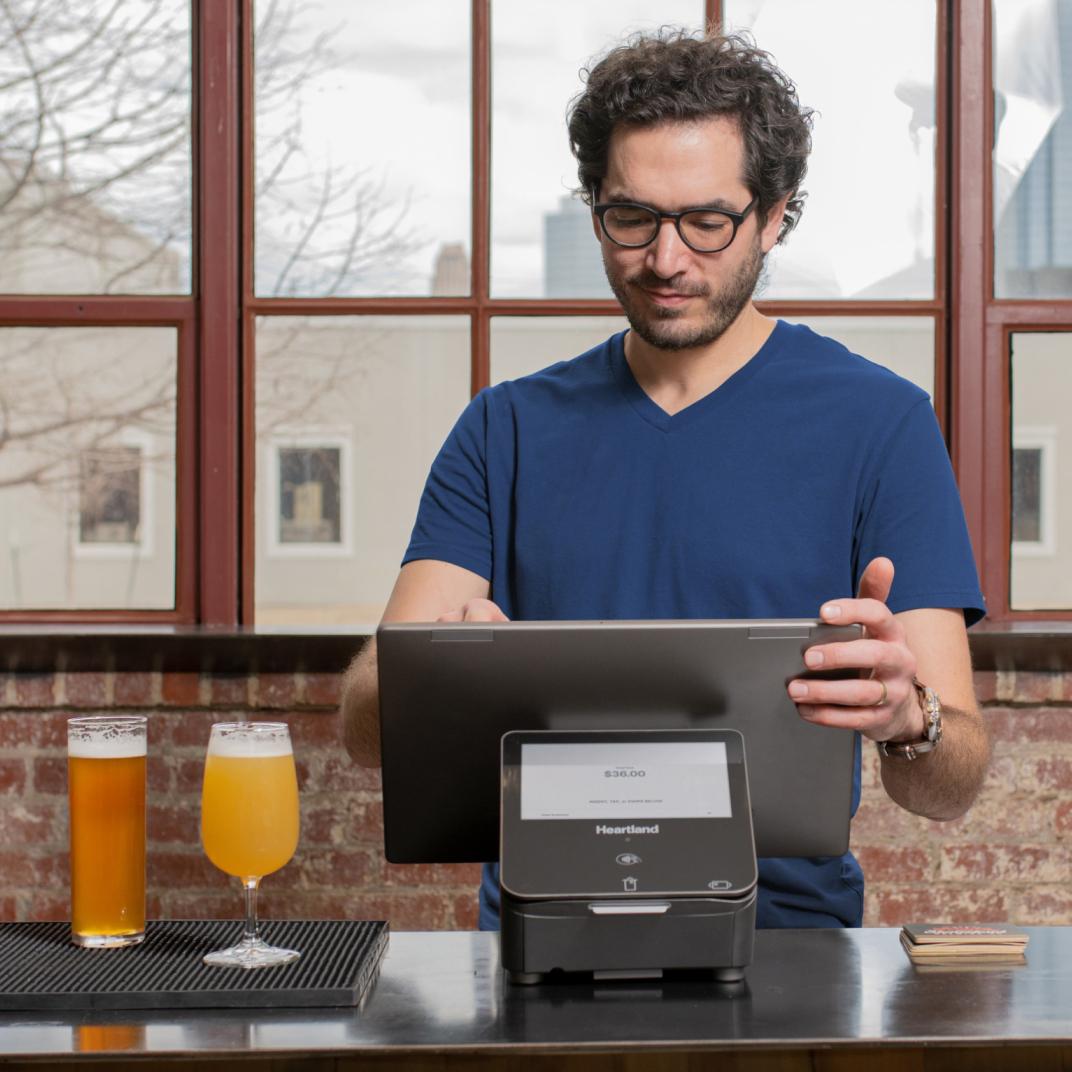 Employee in coffee shop at counter using POS machine