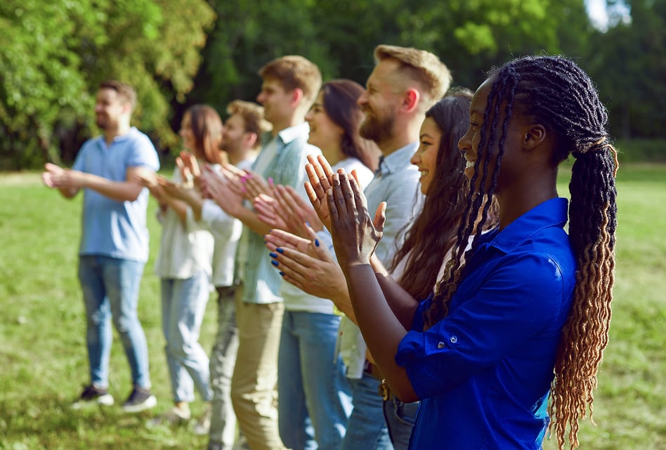 A group of people standing outside smiling and clapping.