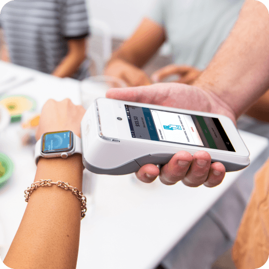 Closeup shot of a customer tapping their Apple watch to a white Genius handheld point of sale to pay for a purchase