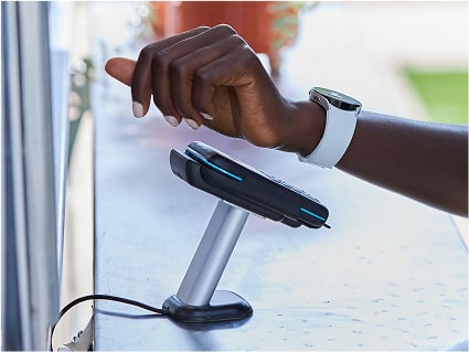 A customer makes a contactless payment with a white wearable watch.