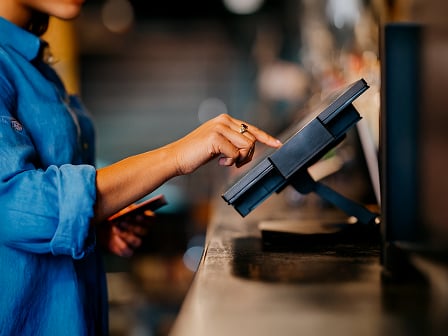 Customer keys in card digits on a countertop card machine.