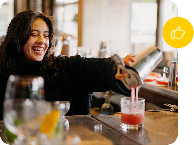 Bartender mixes a Cosmopolitan and pours it into a cocktail glass.