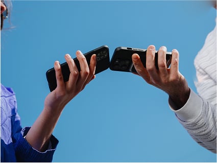 Two phones held by two hands touching mid-air.