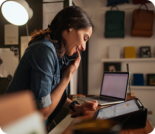 Small business owner speaks on phone with customer support to get help with technology.