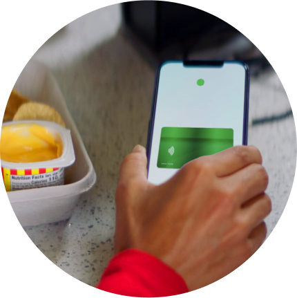 Close-up of hand holding smartphone displaying green digital card interface next to takeout meal container