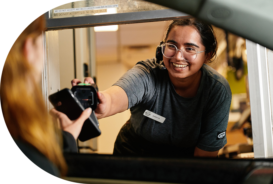 A drive-thru employee smiling while preparing orders in a kitchen. 