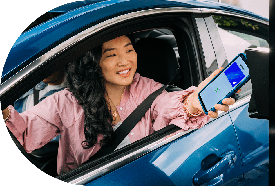 Woman smiling while using contactless payment with her phone in a drive=thru