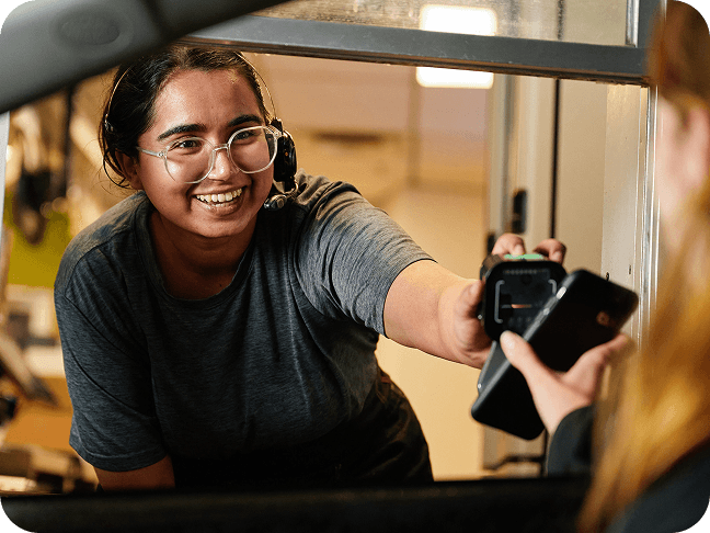A drive-thru employee smiling while preparing orders in a kitchen.