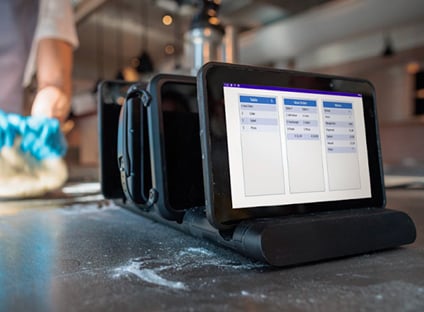 A person uses Genius Enterprise POS software on a touchscreen device.