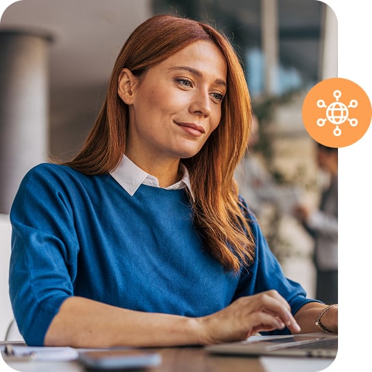 A person in a blue shirt types on a laptop.