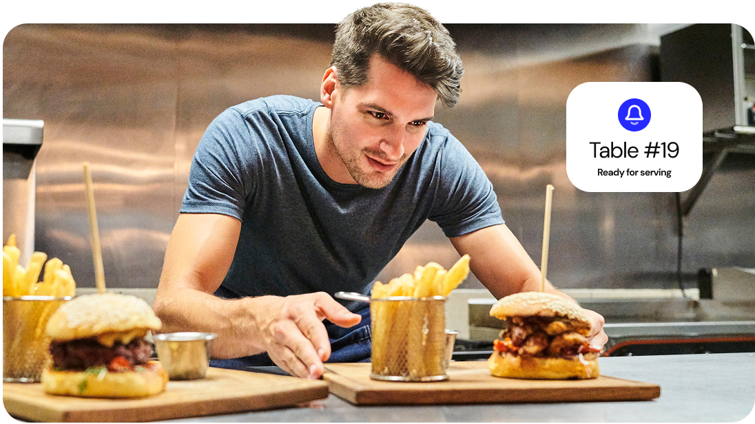 A server picks up a meal from the kitchen to deliver it to a customer.