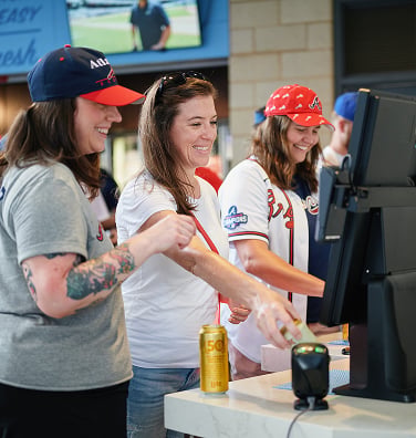 Three women getting napkins and condiments at stadium