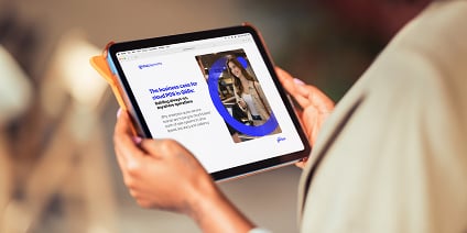 Person viewing a tablet with a white-and-blue report page featuring a headline and a woman’s photo.