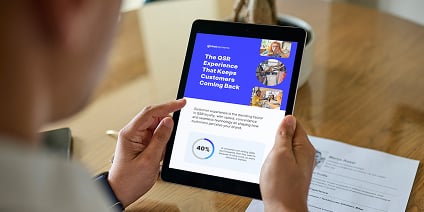 Person holding a tablet with a blue report page titled “The QSR Employee Experience That Keeps Customers Coming Back.”