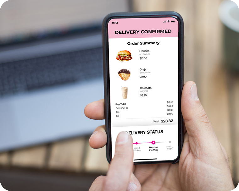 A person holds up a phone that displays the interface for a food ordering app on the screen.