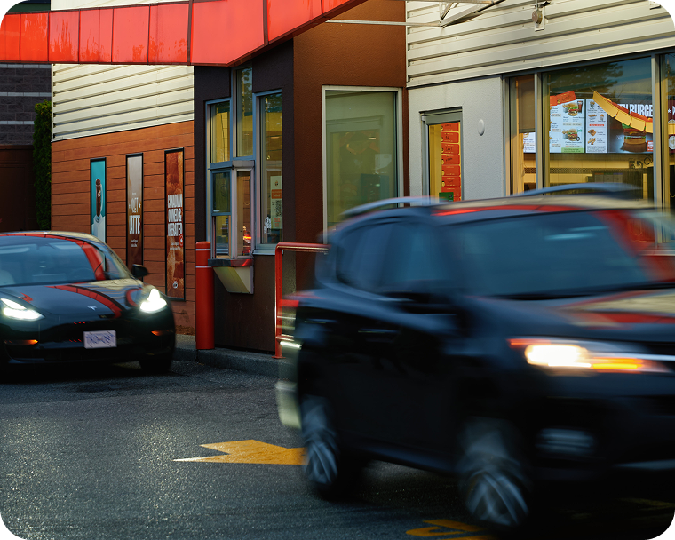 A person sits in a car while ordering food at a drive thru.