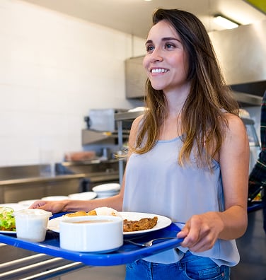A person working in a restaurant hands a woman a cup of coffee.