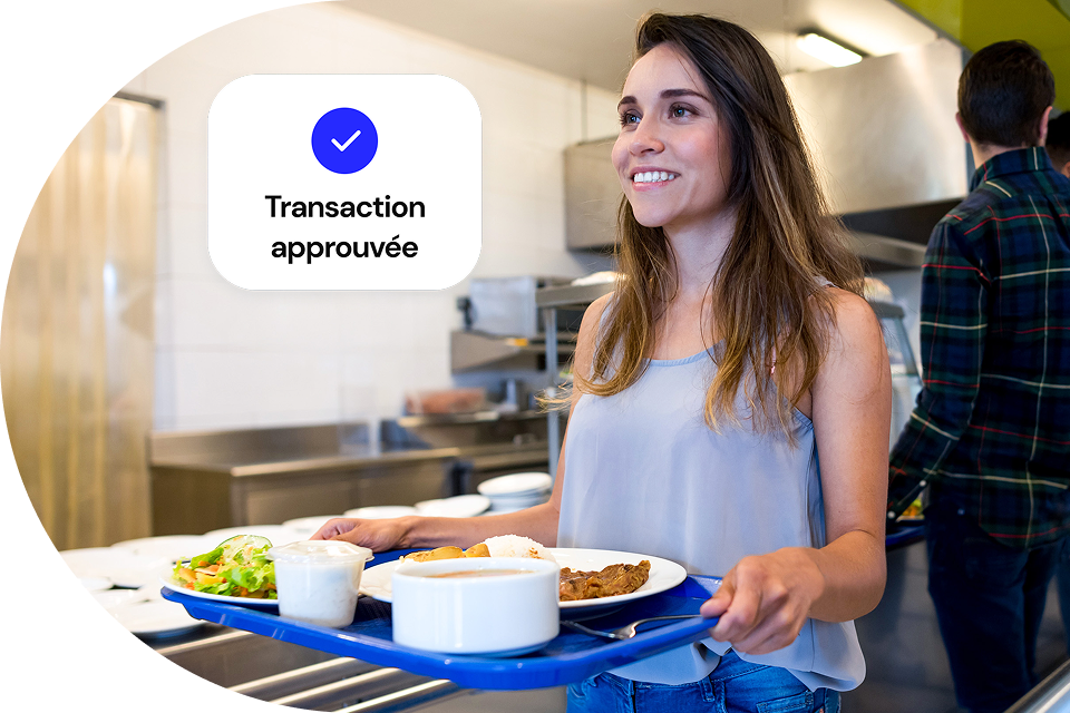 Après avoir effectué une transaction, une cliente de la cafétéria transporte un plateau de nourriture jusqu’à sa place.