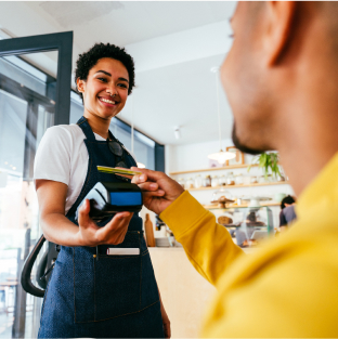 A cashier holds out a card machine, as a customer swipes his credit card payment.