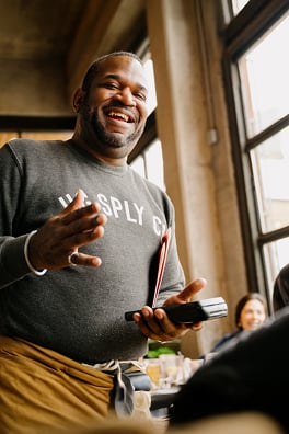 A restaurant server greets his customers with a handheld point of sale.