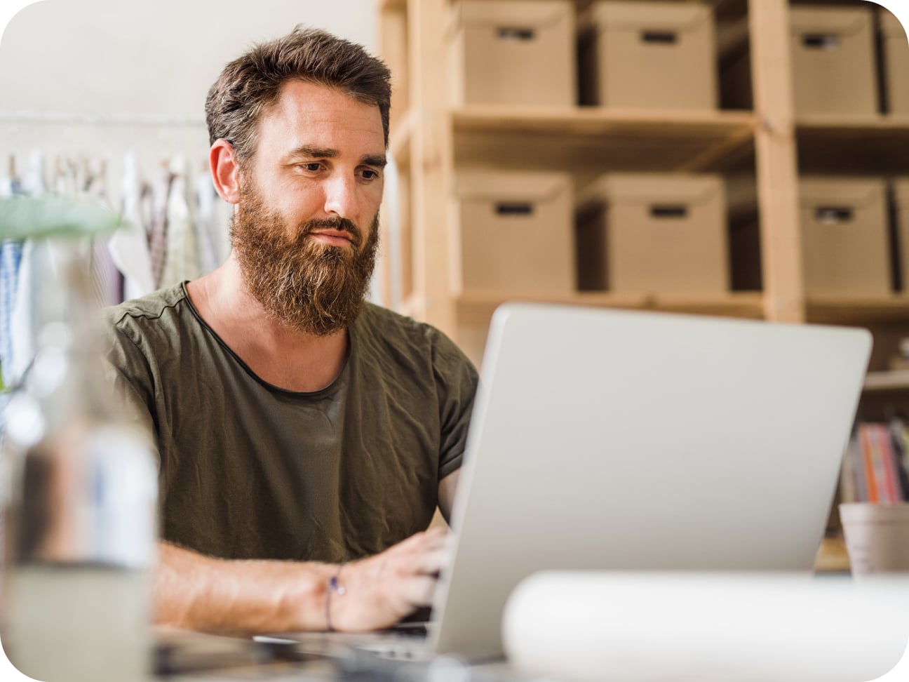 A business owner checks his inventory on his laptop in a storage room