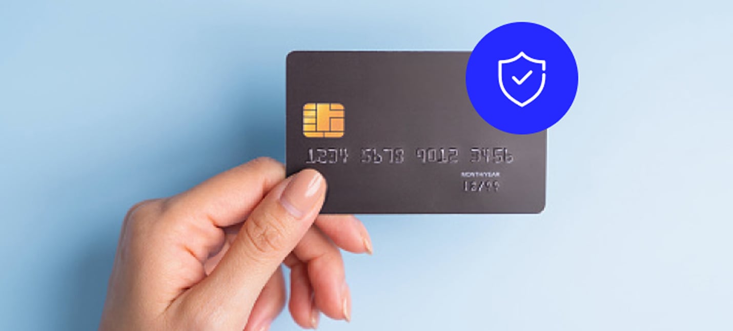 A person holding a payment card equipped with EMV technology.