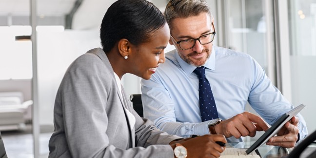 Two agent bank partners reviewing a tablet and smiling