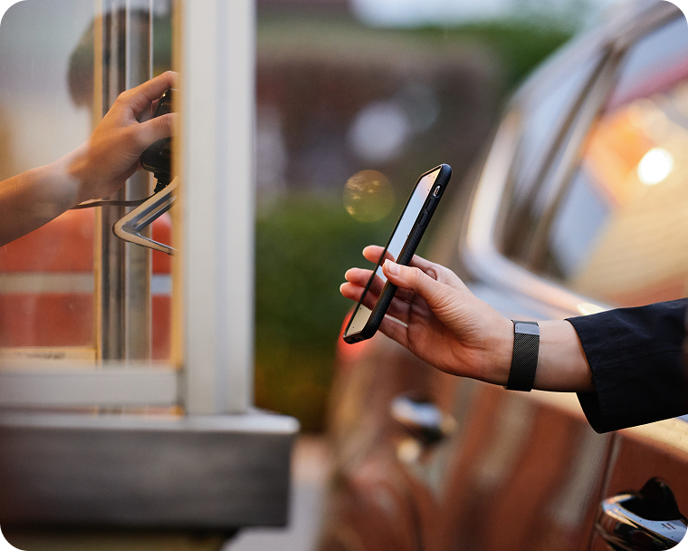 A quick service employee accepts a customer’s mobile payment in the drive thru.