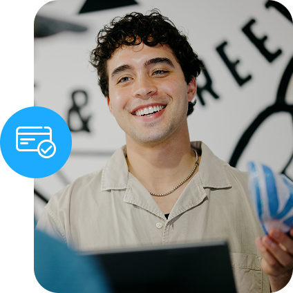Retail worker smiles while helping a customer check out at a countertop point of sale.