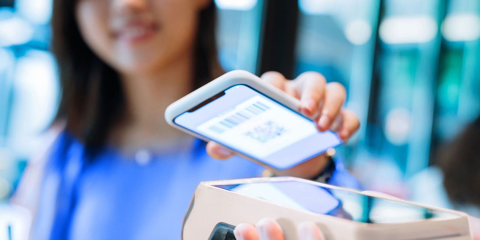 Customer holding smartphone over handheld POS device