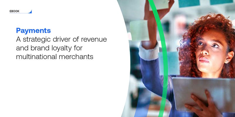 Cover of ebook titled "Payments: a strategic driver of revenue and brand loyalty for multinational merchants“ depicting person holding tablet and looking at glass wall covered in sticky notes