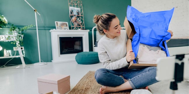 Woman sitting on the floor in living room opening a package