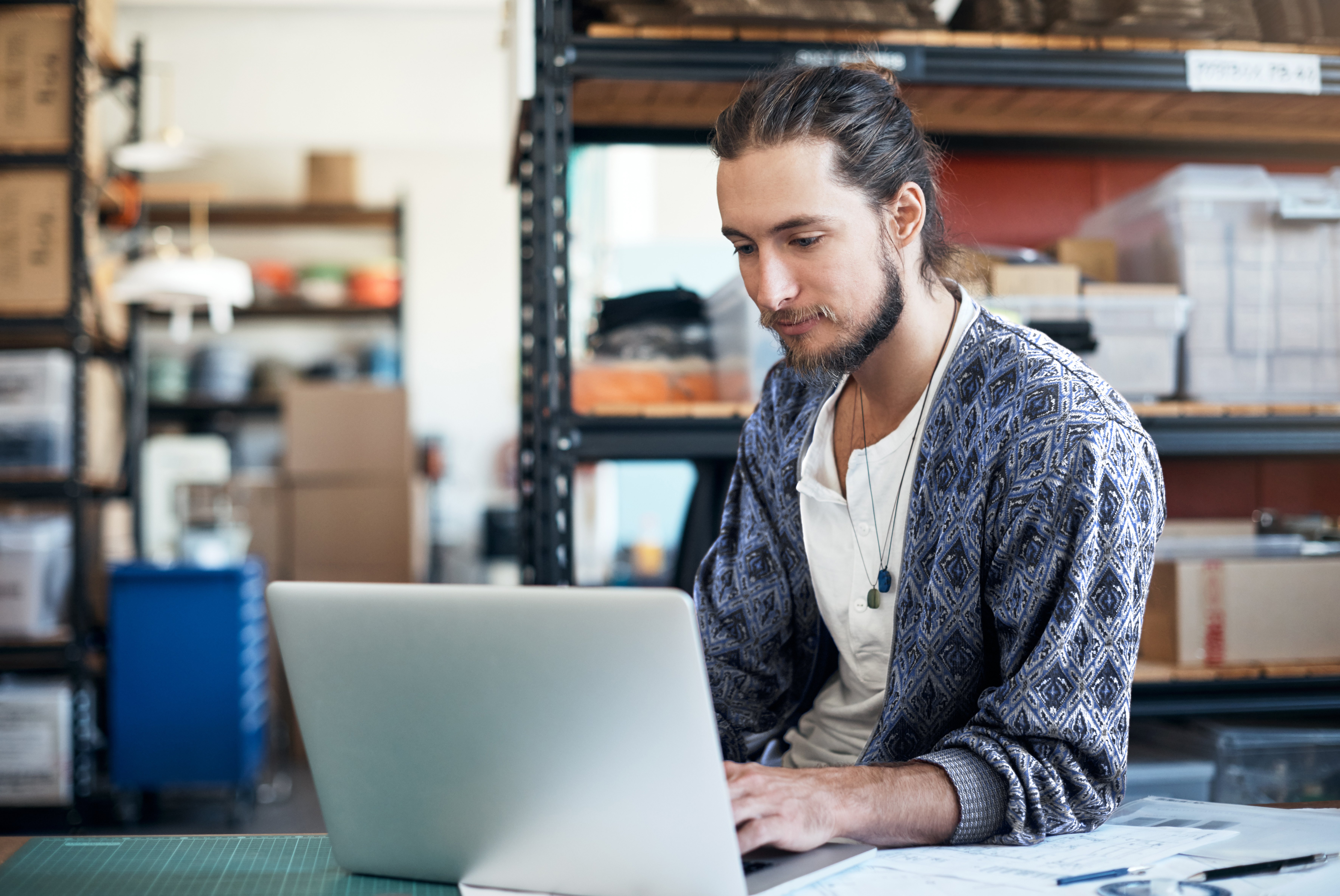 Seated person works on laptop in stockroom setting