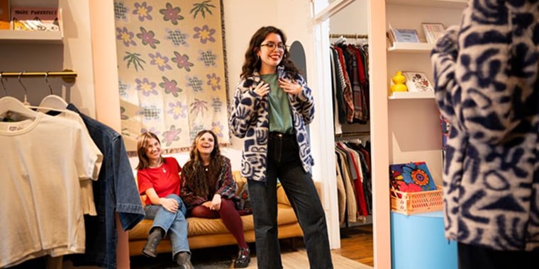 Woman trying on clothes and being admired by friends watching on a couch