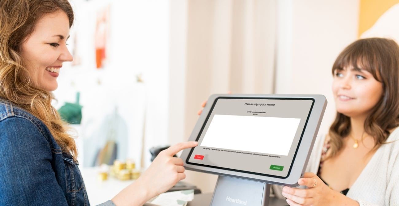 Customer entering signature at point of sale terminal in presence of retail worker