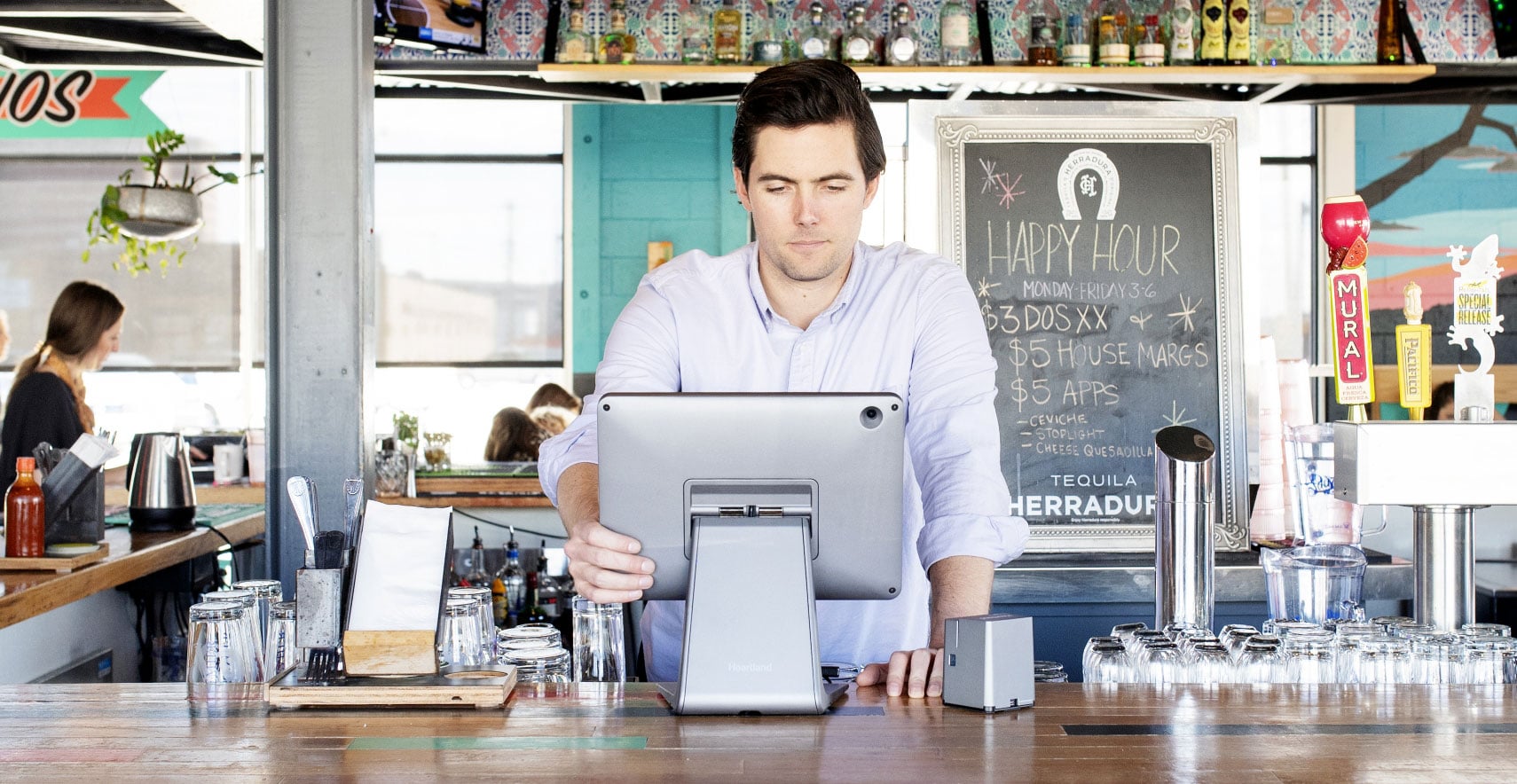 Restaurant worker uses point of sale system while standing behind bar in server area