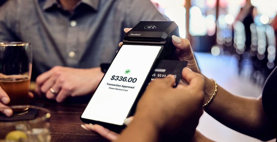Close up shot of customer inserting their credit card into a restaurant mobile POS held by a server
