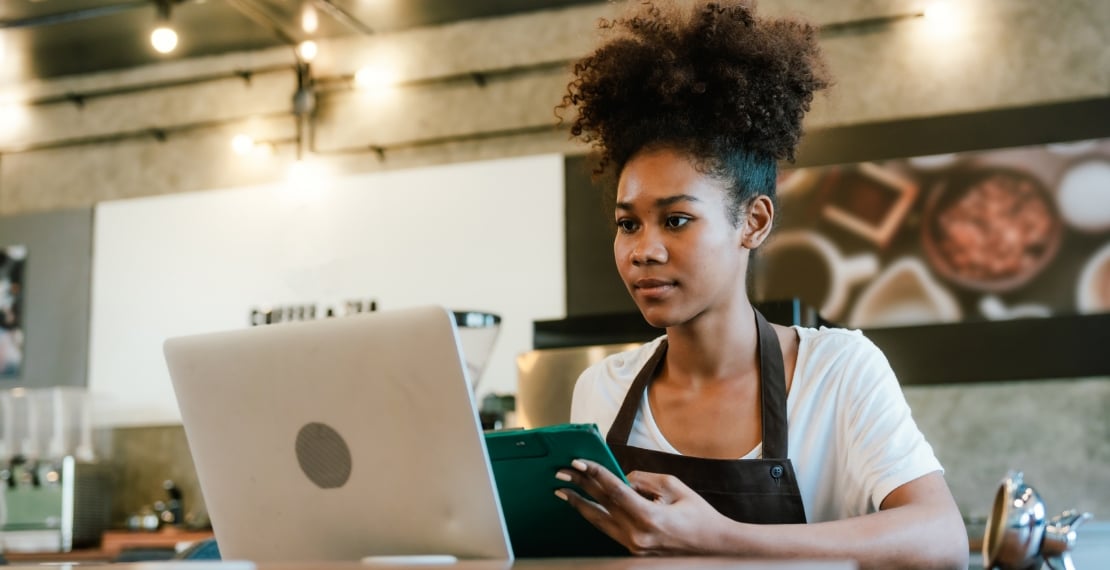 Restaurant worker looks up profit margin information on laptop and iPad.
