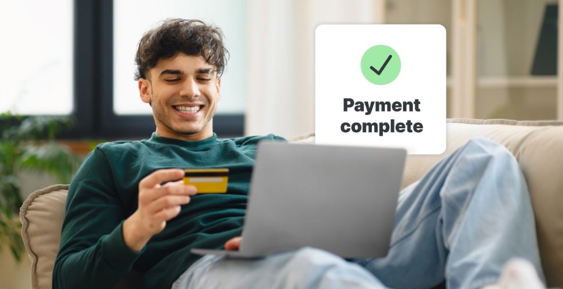 A smiling customer on his couch completes a card payment at his laptop