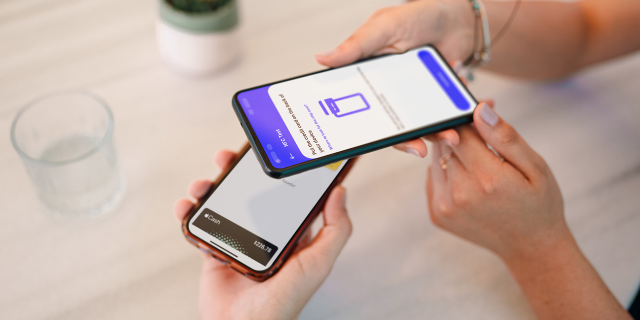 Hands holding two smartphones inches apart during a mobile payment interaction. 