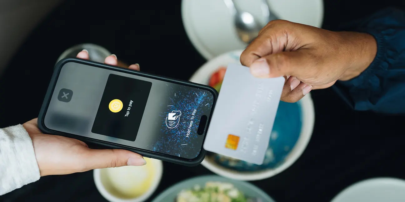 A customer taps a credit card against a smartphone to complete a contactless payment.